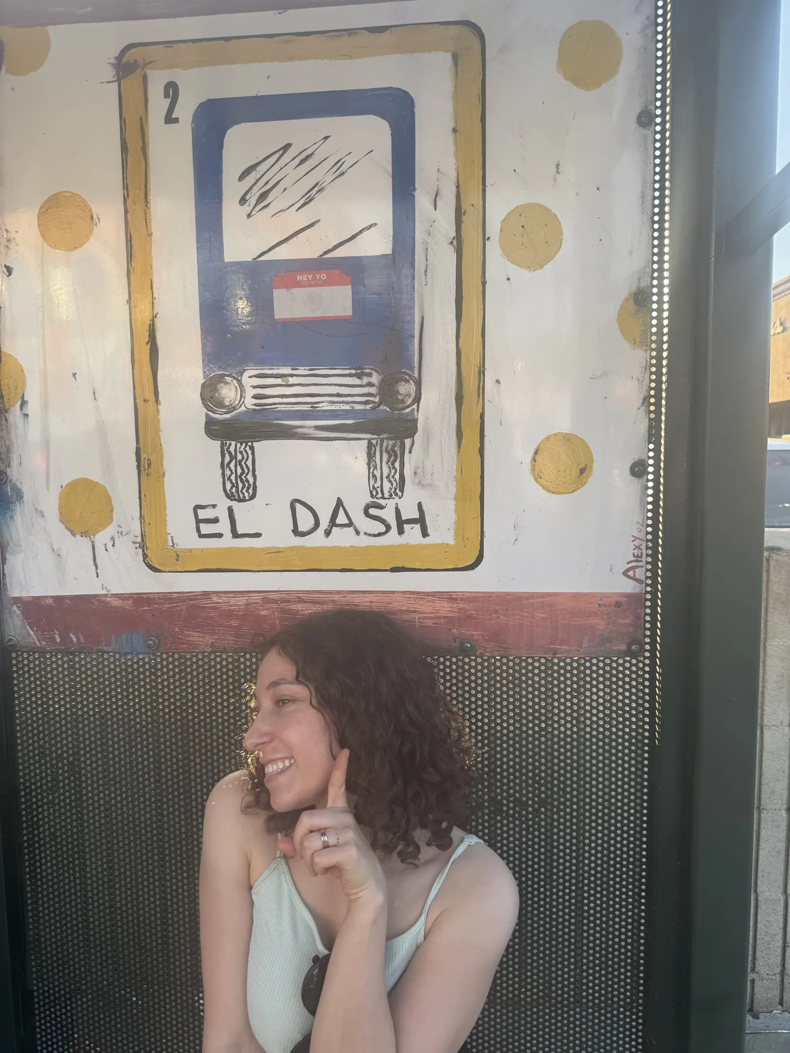 Dashiell's sister smiling in front of a painted El Dash bus stop sign in Los Angeles.