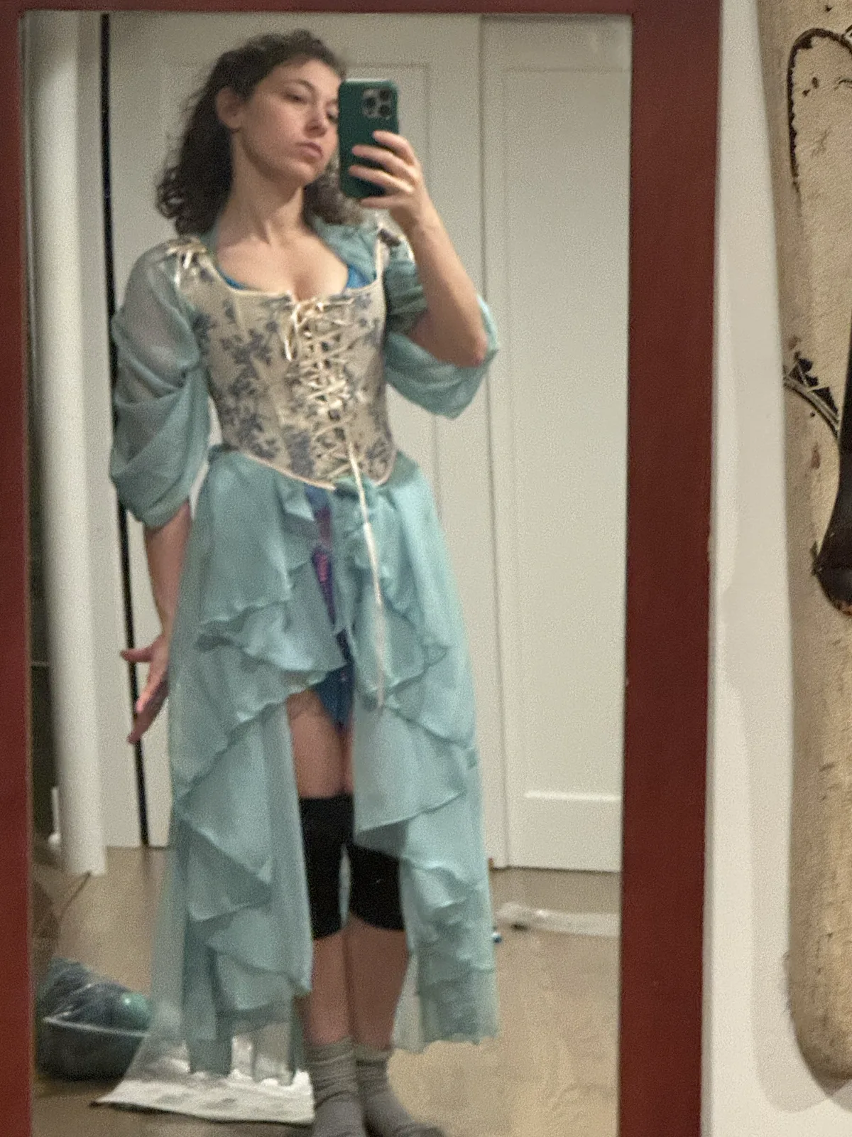 Mirror selfie wearing a pale blue corset with a layered light blue outfit and sheer wrap.