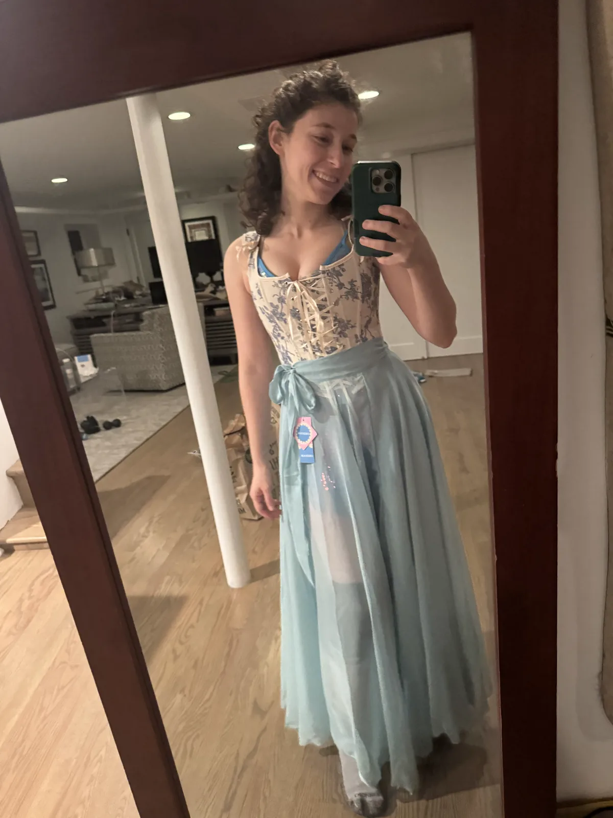 Smiling mirror selfie wearing a pale blue corset with a long light blue skirt.